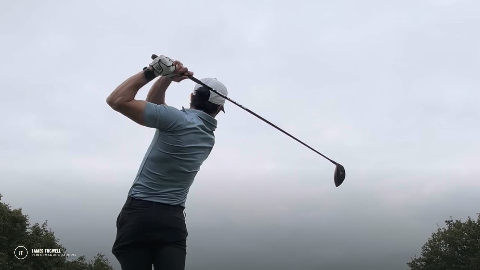James Tugwell at the top of his follow-through after a drive, under a grey winter sky