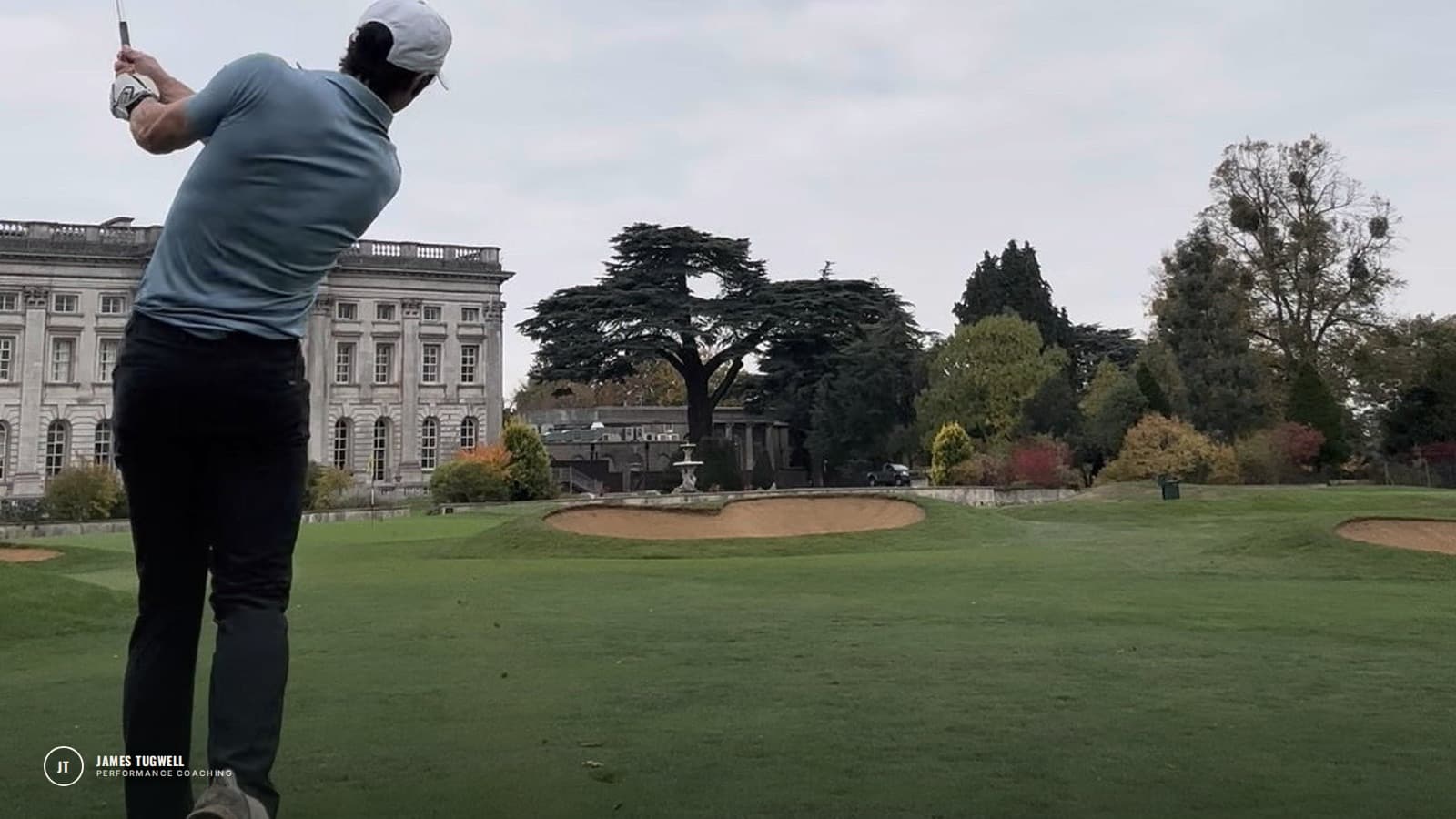James Tugwell hitting an approach shot on an autumn golf course in front of a country house