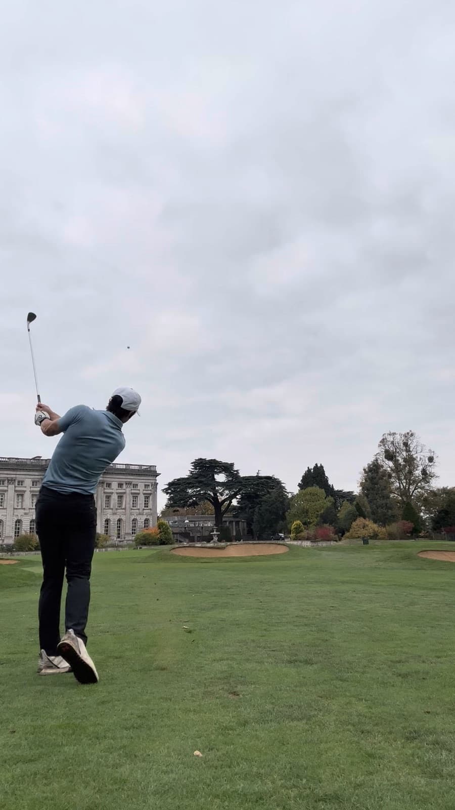 James following through on a drive in front of a country house